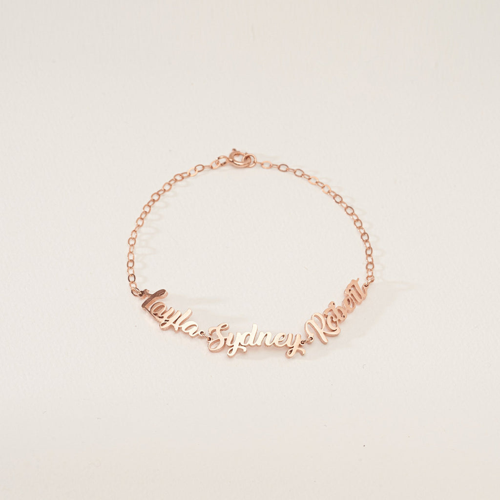 The Classic Multiple Name Bracelet features a dainty chain with the names Layla, Sydney, and Rowan in elegant cursive—perfect personalized jewelry for any occasion.