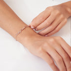 A person wears a Classic Multiple Name Bracelet with cursive script on their wrist, set against a white background.