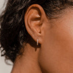 A close-up of an ear adorned with Vera Pave Huggies—elegant, gold minimalist hoops set with sparkling diamonds, ideal for everyday jewelry lovers.