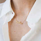 The Dainty Name Necklace gleams with a personalized touch, perfect for adding minimalist style to any outfit, like layering it over a crisp white collared shirt.