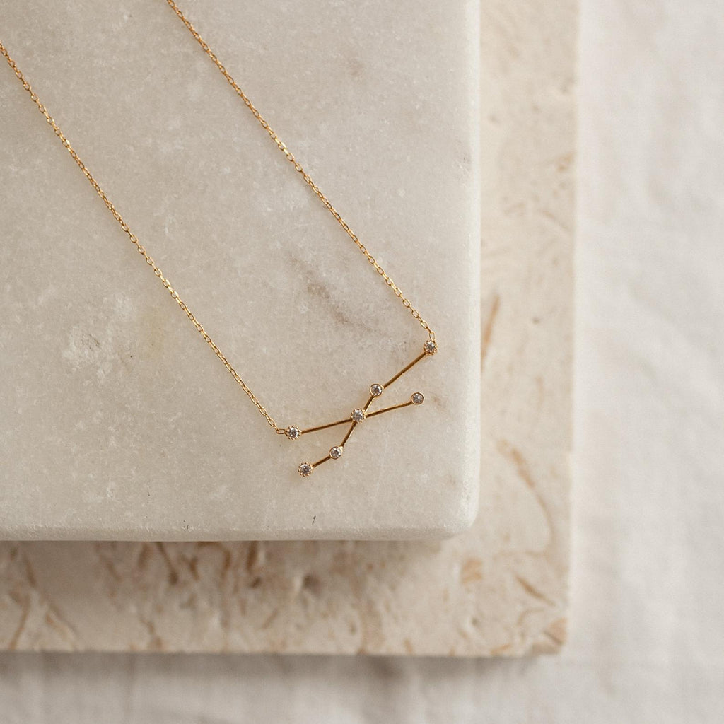 Constellation Necklace featuring a starry pendant, displayed on a marble slab with a neutral background—a celestial-inspired accessory for added charm.