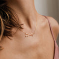 Close-up of a woman's neck wearing the gold Constellation Necklace paired with a pink spaghetti strap top.