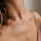 A woman wearing the Constellation Necklace, a delicate gold accessory with a minimalist design that reflects the beauty and elegance of the night sky.