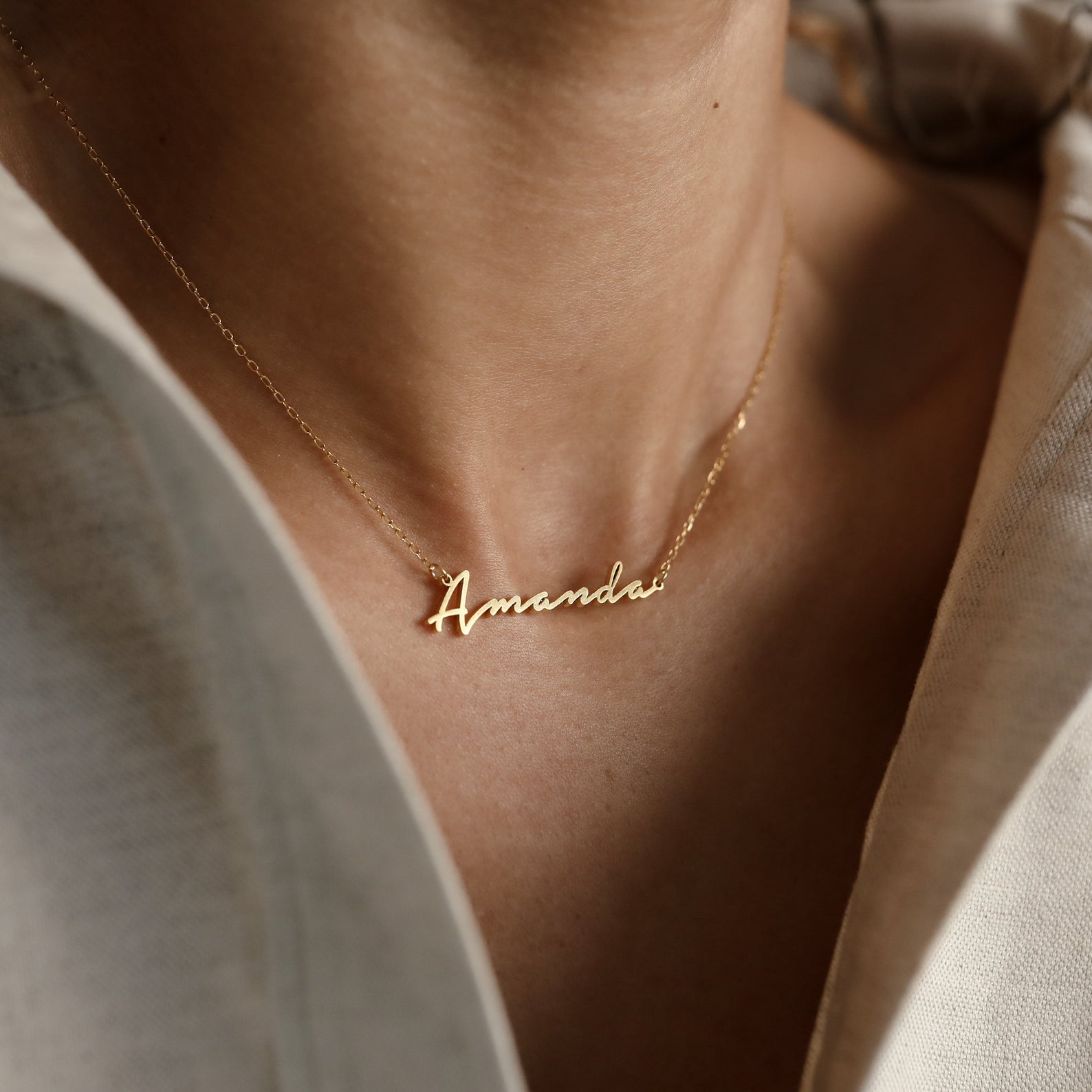 The Minimal Name Necklace displays the name "Amanda" in elegant cursive and is worn as a stylish, personalized accessory—ideal for gifting.