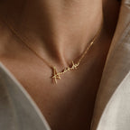 The Summer Name Necklace features a gold personalized pendant spelling "Amanda" in an elegant script font, shown worn around the neck in a close-up view.