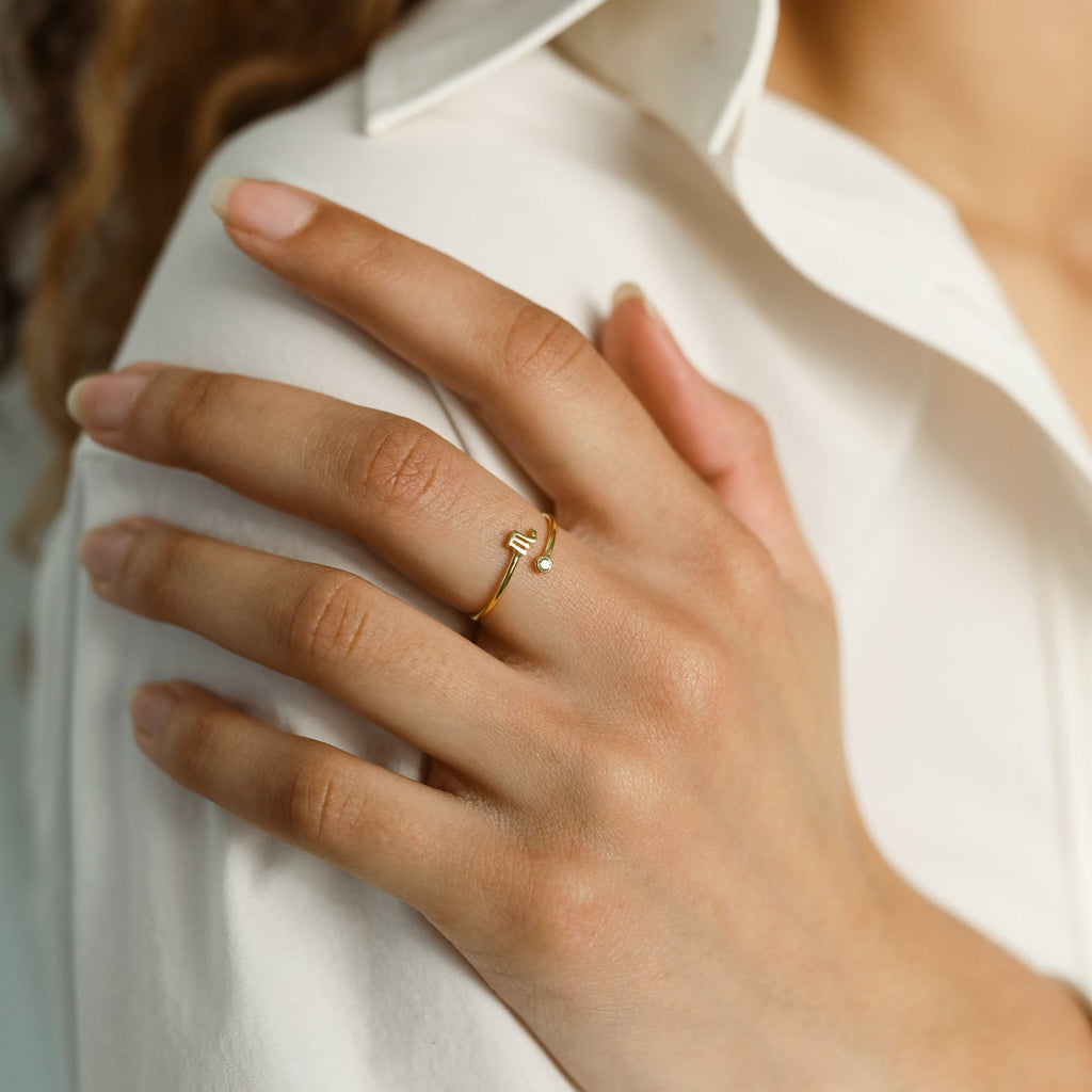 A hand with neatly manicured nails and elegant jewelry rests on a white shirt, showcasing the Zodiac Birthstone Ring.