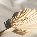 Four gold earrings—some featuring stones—rest on a dried palm leaf over light fabric, perfectly matching elegant jewelry such as the Zodiac Birthstone Ring for a refined touch.