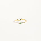 The Zodiac Birthstone Ring features a gold band with the Taurus symbol and a small green birthstone, combining elegant jewelry with celestial charm on a plain white background.