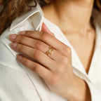 A hand wearing the London Duo Name Ring rests on a white shirt, highlighting neatly manicured nails and curly brown hair.