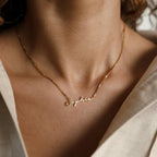 The Venice Name Necklace in Box Chain, customized with the name Sophia, shines elegantly on a wearer dressed in a cream-colored shirt.
