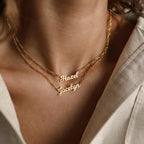 Two Mellow Name Necklaces in Figaro Chain, personalized with "Hazel" and "Jocelyn," are worn together. Each gold necklace features a sleek Figaro chain for an elegant touch.