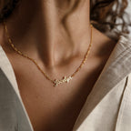 A Mellow Name Necklace in Figaro Chain, personalized with the name Jacelyn, shown worn by a person in a cream-colored shirt.