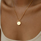 Spinner Pendant Necklace with a round pendant engraved with the letter A, shown on a model in a beige top. The spinning feature adds an interactive touch to this elegant accessory.