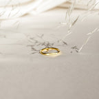 The Ann Skinny Name Ring in Rose Gold, engraved with "Selena," rests on a light beige surface with delicate plant shadows—a perfect Christmas gift for her.