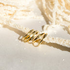 Four Ann Skinny Name Rings with engraved names are shown on a cream textured surface in soft light—a perfect stacking ring set and thoughtful Christmas gift for her.