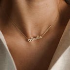 Close-up of a Mellow Name Necklace featuring the name Amelia in gold cursive, worn on a woman's neck.