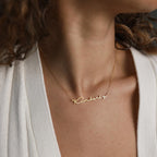 The Minimal Name Necklace in gold, featuring "Kimberly" in script, rests elegantly around her neck—a personalized gift to treasure.