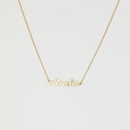 The Mellow Name Necklace features a gold chain and a pendant spelling "Amelia" in elegant cursive, making it an ideal personalized necklace for any special occasion.
