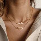 Close-up of a woman wearing two gold Mellow Name Necklace in Box Chain, personalized with "Amelia" and "Aubrey", each displayed on sleek box chains for a modern look.