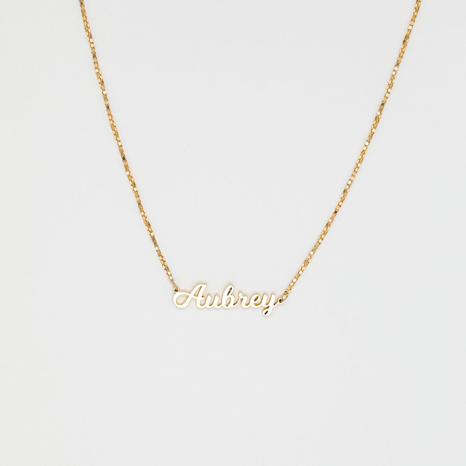 The Mellow Name Necklace in Box Chain features "Aubrey" in elegant cursive on a slim box chain, shown against a white background.