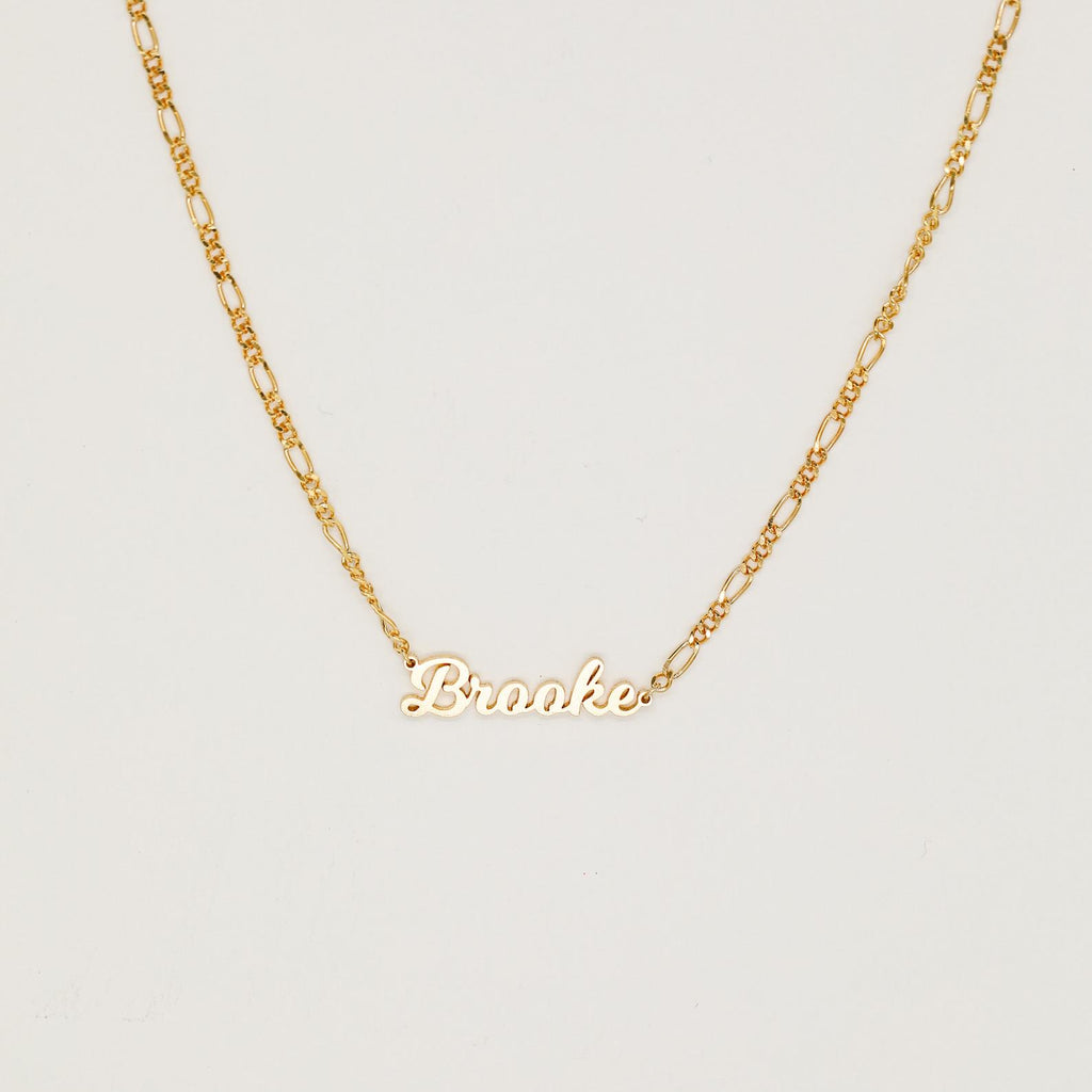 The Mellow Name Necklace in Figaro Chain features "Brooke" in elegant cursive, shown on a classic chain against a plain white background.
