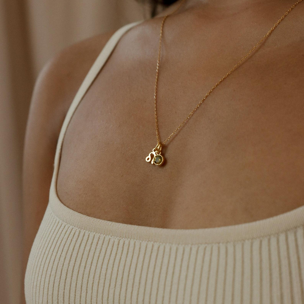 A woman wears a cream ribbed tank top and the Zodiac Birthstone Necklace featuring two small gold pendants.