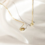 An elegant Interlocking Circles Necklace in silver and gold is displayed on smooth, ivory satin fabric.