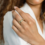 A woman wears the Audrey Ring, featuring a ridged gold design, with a white blouse—an everyday essential for understated elegance.