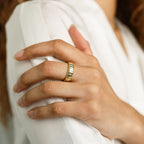 A hand wearing the Audrey Ring rests on the opposite arm, both in white long-sleeve shirts—showcasing an effortlessly essential everyday look.