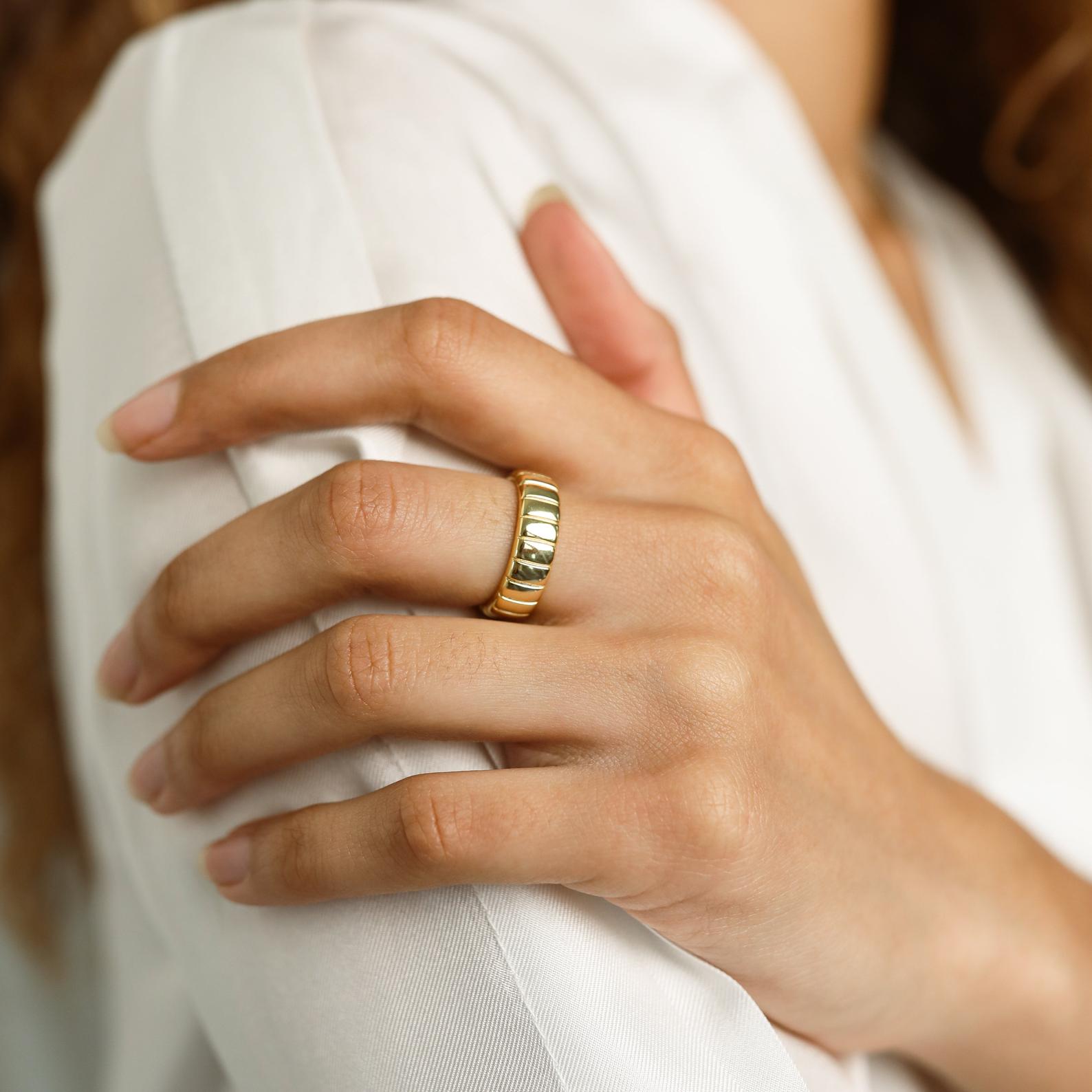 A hand wearing the Audrey Ring rests on the opposite arm, both in white long-sleeve shirts—showcasing an effortlessly essential everyday look.