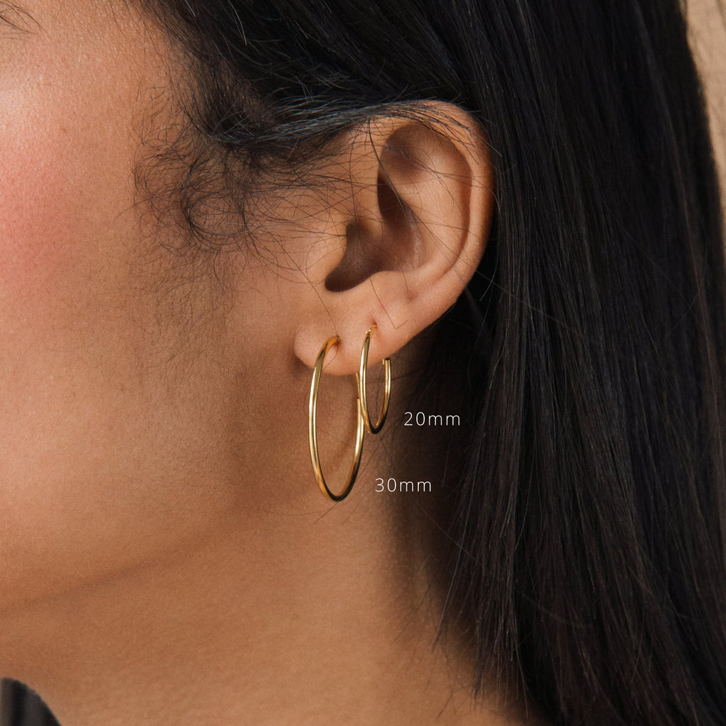 Close-up of an ear with straight dark hair, wearing Large Thin Hoops in 20mm and 30mm—an ideal simple hoop earring choice for everyday style.
