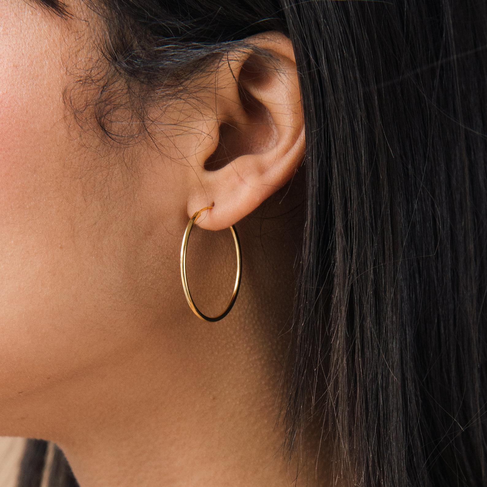 Close-up of a person with straight dark hair wearing Large Thin Hoops—an effortless addition to any everyday wardrobe.