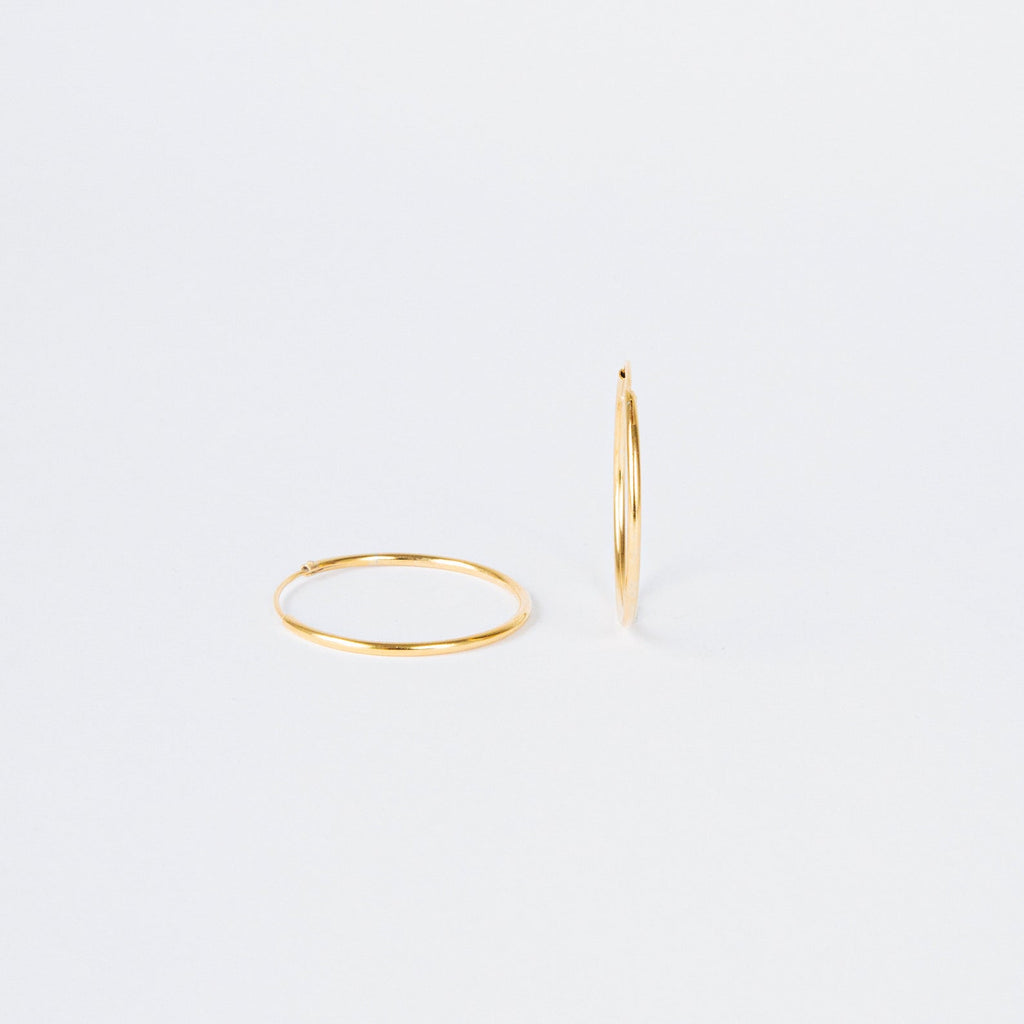 Large Thin Hoops—one flat, one upright on a plain white background. These simple earrings offer versatile, timeless style, making them an effortless addition to any everyday wardrobe.