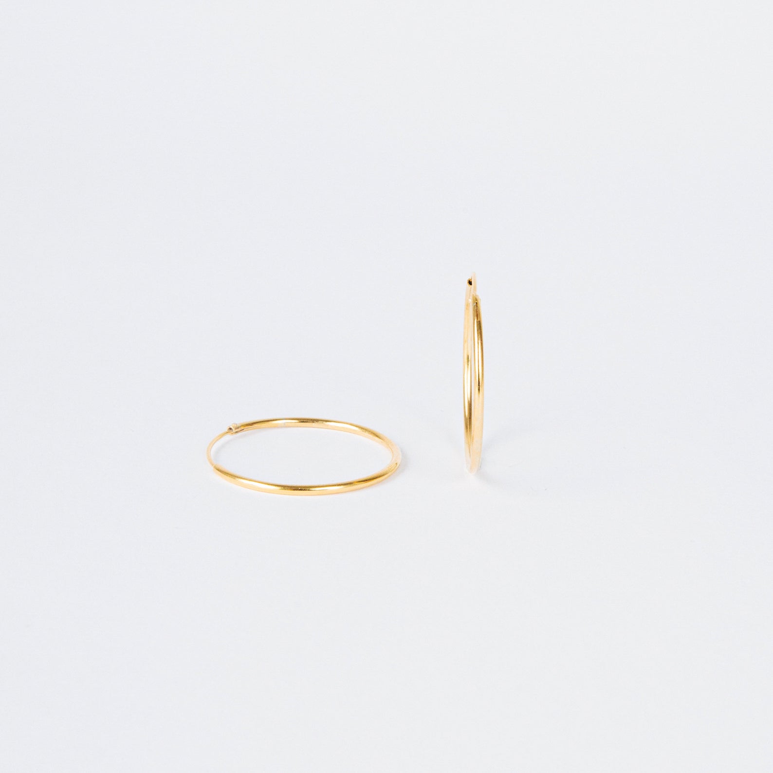 Large Thin Hoops—one flat, one upright on a plain white background. These simple earrings offer versatile, timeless style, making them an effortless addition to any everyday wardrobe.