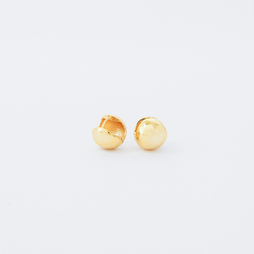 A pair of small, shiny gold Chunky Ball Hoops on a white background adds a touch of 70’s-inspired style to any look.