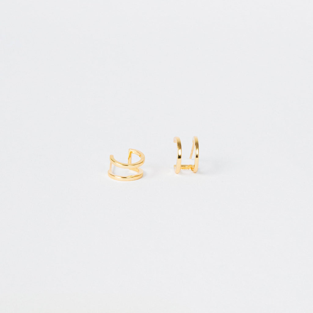 Twin Hoops: Minimalist gold ear cuffs displayed on a plain white background, creating a chic double earring illusion.