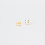 Twin Hoops: Minimalist gold ear cuffs displayed on a plain white background, creating a chic double earring illusion.