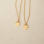 Two gold Spinner Pendant Necklaces with round pendants—one engraved with the letter A, the other with the name Alison—each featuring a unique spinning detail.