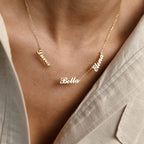 Worn over a beige collared shirt, the Carrie Multiple Name Necklace in gold displays Luna, Bella, and Elena in an elegant personalized design.