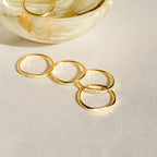 The Ann Skinny Name Ring in Rose Gold, engraved with names, is shown near a marble bowl on a light textured surface—making it a perfect Christmas gift for her.