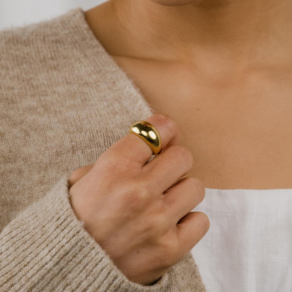 A person wearing the Bold Dome Ring with a beige sweater layered over a white top.