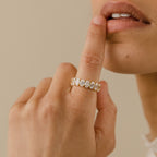 A hand wearing the Alannah Ring, featuring an elegant oval diamond, gently touches parted lips against a neutral background.