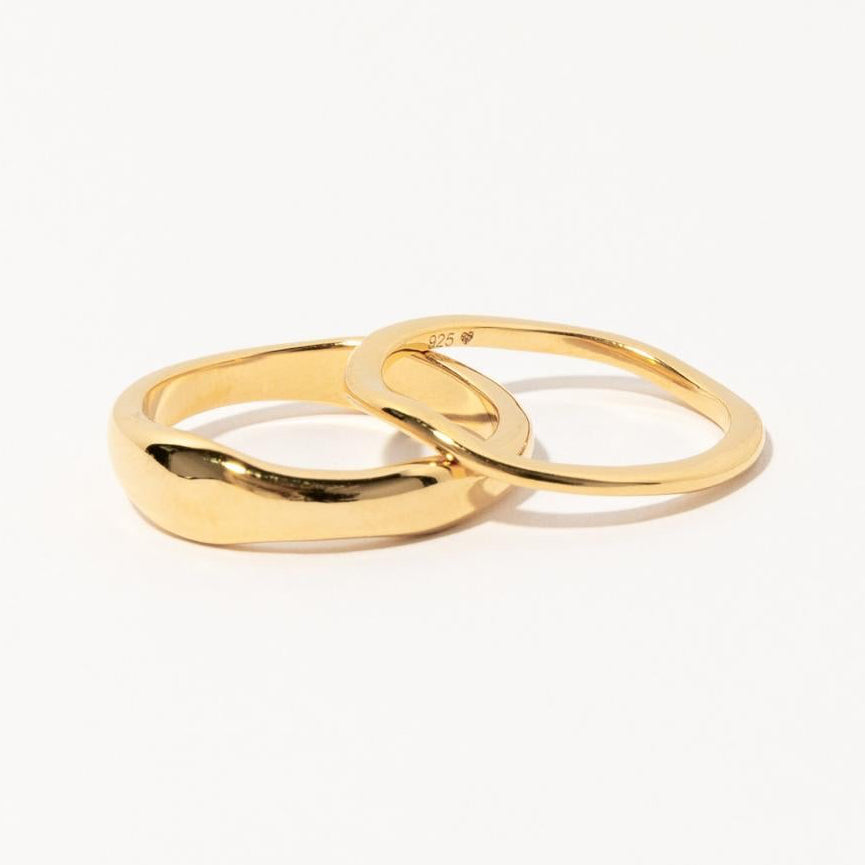 Two interlocking gold rings from the Duo Form Ring Set displayed on a clean white background.