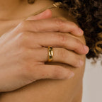 A hand wearing the Star Dome Ring, a gold band adorned with sparkling diamonds in tiny star shapes, gently rests on a shoulder near curly hair.