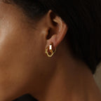 A person wearing Audrey Huggies—small, chunky gold earrings that make an effortless everyday accessory.