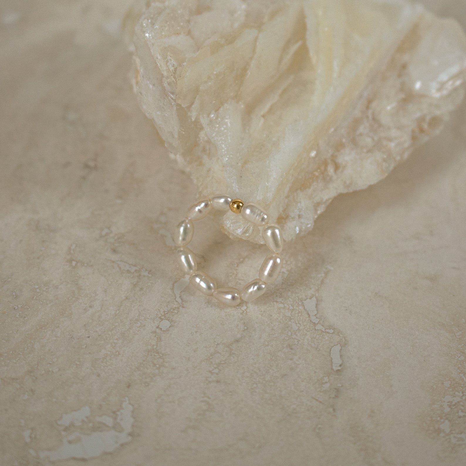 Elegant and stylish, the Pearl Beaded Ring features freshwater pearls and a single gold bead, beautifully showcased on a textured stone surface.