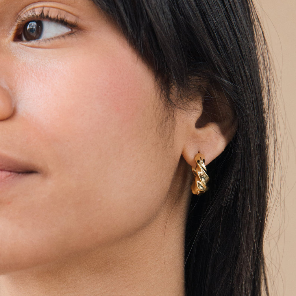 Close-up of a woman wearing the Diana Hoops gold croissant earring on her left ear.