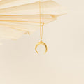 Gold crescent moon pendant necklace hanging from a delicate chain, styled against folded cream-colored paper fans for a soft, minimal backdrop.






Ask ChatGPT
