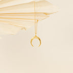 Gold crescent moon pendant necklace hanging from a delicate chain, styled against folded cream-colored paper fans for a soft, minimal backdrop.






Ask ChatGPT
