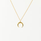 The Crescent Moon Necklace features a gold chain with a delicate crescent moon pendant, shown on a plain white background.
